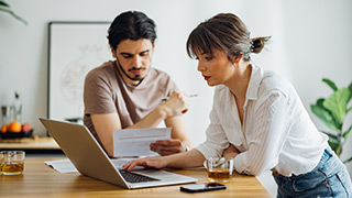 Casal com ar preocupado a fazer contas e ver documentos